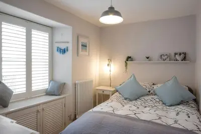 a bedroom with a bed with blue pillows and a window at No3 Gweek in Gweek
