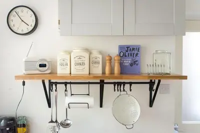 a shelf in a kitchen with a clock on the wall at No3 Gweek in Gweek