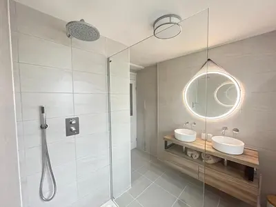 a bathroom with a shower and two sinks and a mirror at No3 Gweek in Gweek