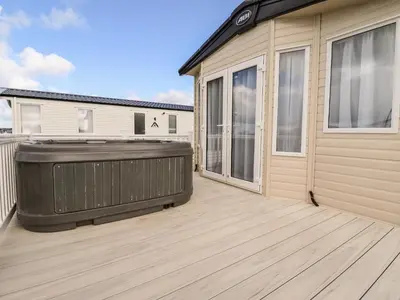 a hot tub on a deck next to a house at 109 Bude in Newquay