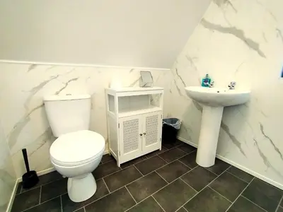 a white bathroom with a toilet and a sink at Tudor Cottage Hayle - a Family & Dog Favourite in Hayle