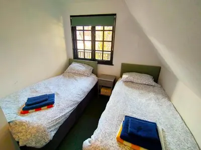 two twin beds in a room with a window at Tudor Cottage Hayle - a Family & Dog Favourite in Hayle