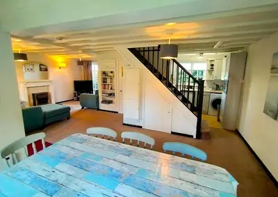 a living room with a table and a staircase at Tudor Cottage Hayle - a Family & Dog Favourite in Hayle