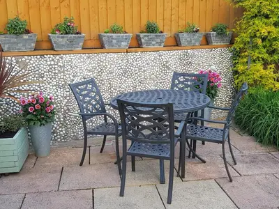 a black table and chairs on a patio with potted plants at Eden's Rest Bed and Breakfast in St Austell