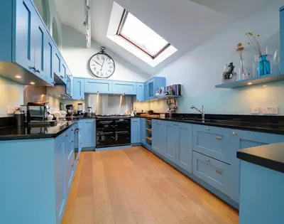 a large kitchen with blue cabinets and a clock on the wall at Camel Point in Wadebridge
