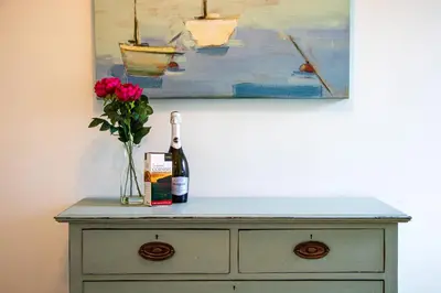a bottle of wine and a vase of flowers on a dresser at Clevedon House - Newquay - Beaches - Parking in Newquay