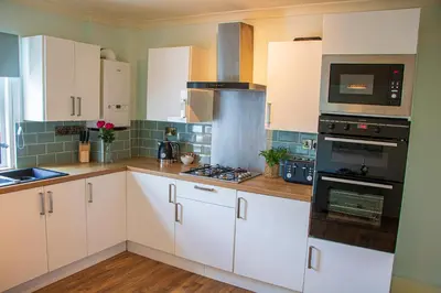 a kitchen with white cabinets and a stove top oven at Clevedon House - Newquay - Beaches - Parking in Newquay