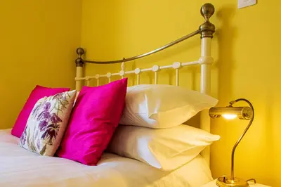 a bed with pink and white pillows and a lamp at Clevedon House - Newquay - Beaches - Parking in Newquay