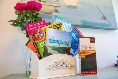 a table with books and a vase with flowers at Clevedon House - Newquay - Beaches - Parking in Newquay
