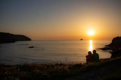 two people sitting on the beach watching the sunset at Clevedon House - Newquay - Beaches - Parking in Newquay