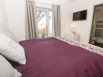 a bedroom with a large purple bed with a window at Perran Pearl A in Perranporth