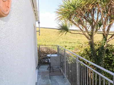 a balcony with a chair and a tree and a field at Perran Pearl A in Perranporth