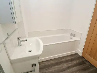 a white bathroom with a sink and a bath tub at Perran Pearl A in Perranporth