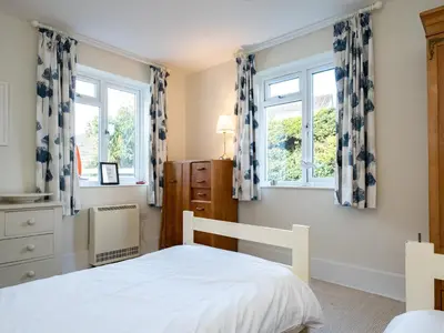 a bedroom with a bed and two windows at Croft Elms in Wadebridge