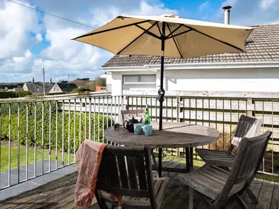 a table and chairs with an umbrella on a deck at Croft Elms in Wadebridge