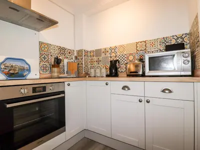 a kitchen with white cabinets and a microwave at EdyVean in St Austell
