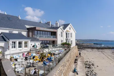 a building on the beach with people sitting at tables at The Godolphin Hotel in Marazion