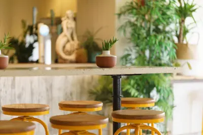 a table with four stools in a room with plants at The Godolphin Hotel in Marazion