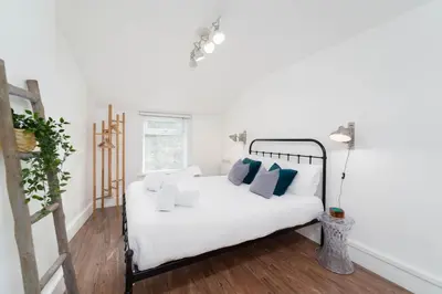 a bedroom with a white bed with blue pillows at Tiddles in St Ives