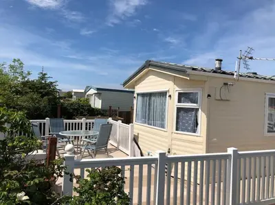 a small house with a white fence and a table at Bluebird K16 in St Merryn