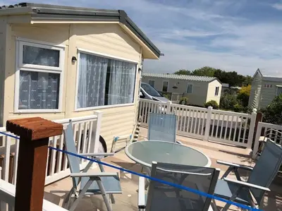 a table and chairs on a deck with a house at Bluebird K16 in St Merryn