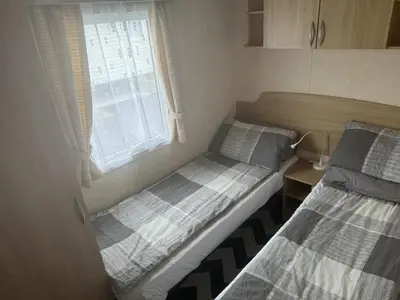 two beds in a small room with a window at Bluebird K16 in St Merryn