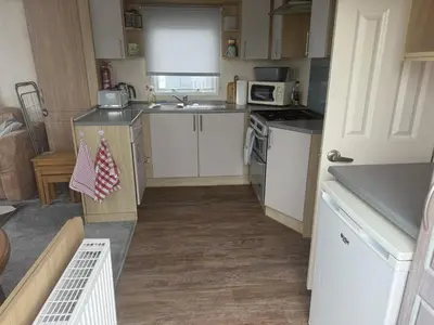 a small kitchen with white cabinets and a sink at Bluebird K16 in St Merryn