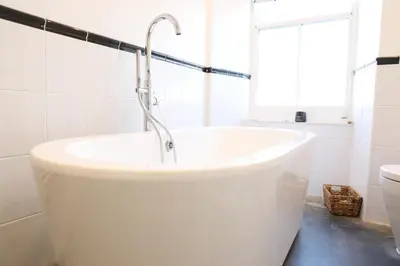 a white bath tub in a bathroom with a window at Stowaway, Port Isaac Bay Holidays in Port Isaac