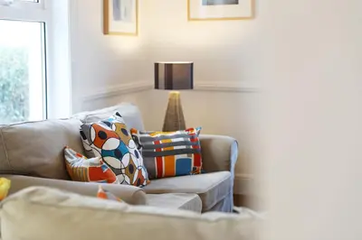 a living room with a couch and a lamp at Tamarisk, Port Isaac Bay Holidays in Port Isaac