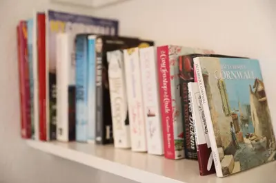 a row of books sitting on a shelf at Tamarisk, Port Isaac Bay Holidays in Port Isaac