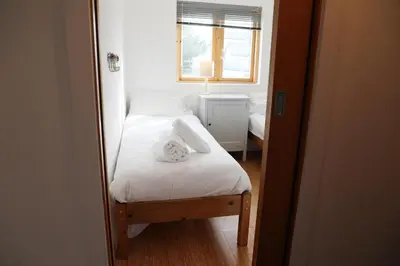 a small bedroom with a bed and a window at Northlight, Port Isaac Bay Holidays in Port Isaac