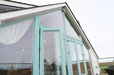 a conservatory with a window with a white curtain at Northlight, Port Isaac Bay Holidays in Port Isaac