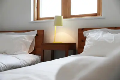 two beds in a room with two windows at Northlight, Port Isaac Bay Holidays in Port Isaac