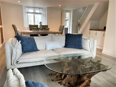 a living room with a couch and a glass table at The Little Seahorse - Newly Renovated Cottage 5mins Walk The Beach with Hot Tub in Tywardreath