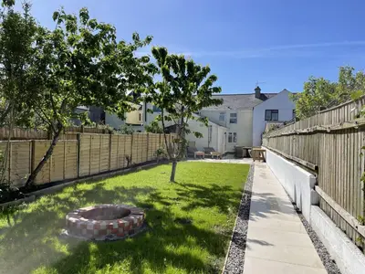 a backyard with a fence and a fire pit at The Little Seahorse - Newly Renovated Cottage 5mins Walk The Beach with Hot Tub in Tywardreath