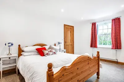 a bedroom with a bed with white sheets and red curtains at Eveley Cottage in Boscastle