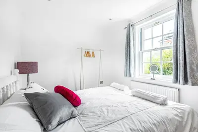 a white bedroom with a large bed with red pillows at Eveley Cottage in Boscastle