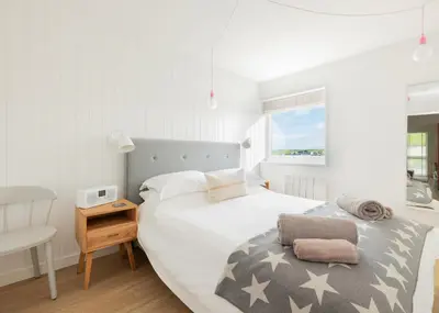 a white bedroom with a bed and a window at Westward 8 in Polzeath
