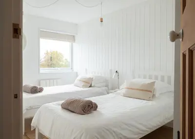 two beds in a room with white walls and a window at Westward 8 in Polzeath