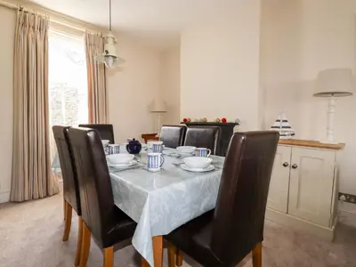 a dining room table with black chairs and a table cloth at Driftwood in Fowey