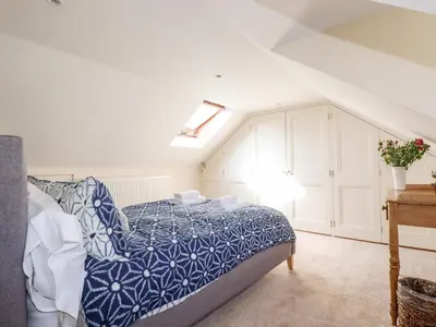 a bedroom with a bed with a blue comforter at Driftwood in Fowey