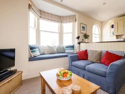 a living room with couches and a bowl of fruit on a table at Driftwood in Fowey