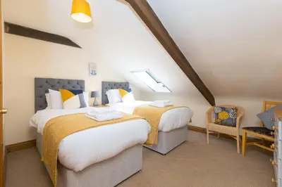 a bedroom with two beds and a chair at FurnessThe West Dry in St Austell
