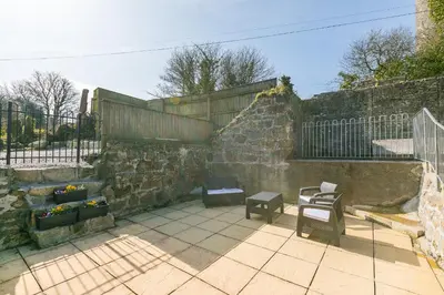 a patio with two chairs and a stone wall at FurnessThe West Dry in St Austell