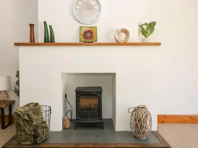 a living room with a fireplace with a clock on the wall at FurnessThe West Dry in St Austell
