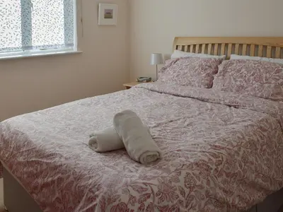 a white towel laying on a bed in a bedroom at Hazel Cottage in Budock Water