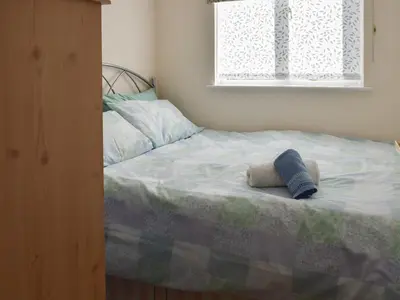 a bedroom with a bed with two pillows and a window at Hazel Cottage in Budock Water