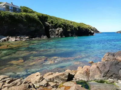 a body of water with rocks in front of a beach at Trevose, sea views in Port Isaac
