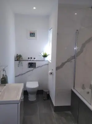 a white bathroom with a toilet and a shower at Trevose, sea views in Port Isaac