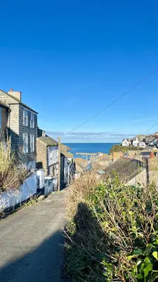 a house on the side of a road next to the ocean at Lobster Cove, Excellent location, Close to beach & coastal walks, Family run in Port Isaac